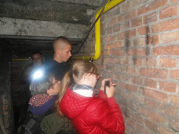 Uczniowie fotografują inskrypcje wyryte przez więźniów aresztu przy ul. Strzeleckiej 8